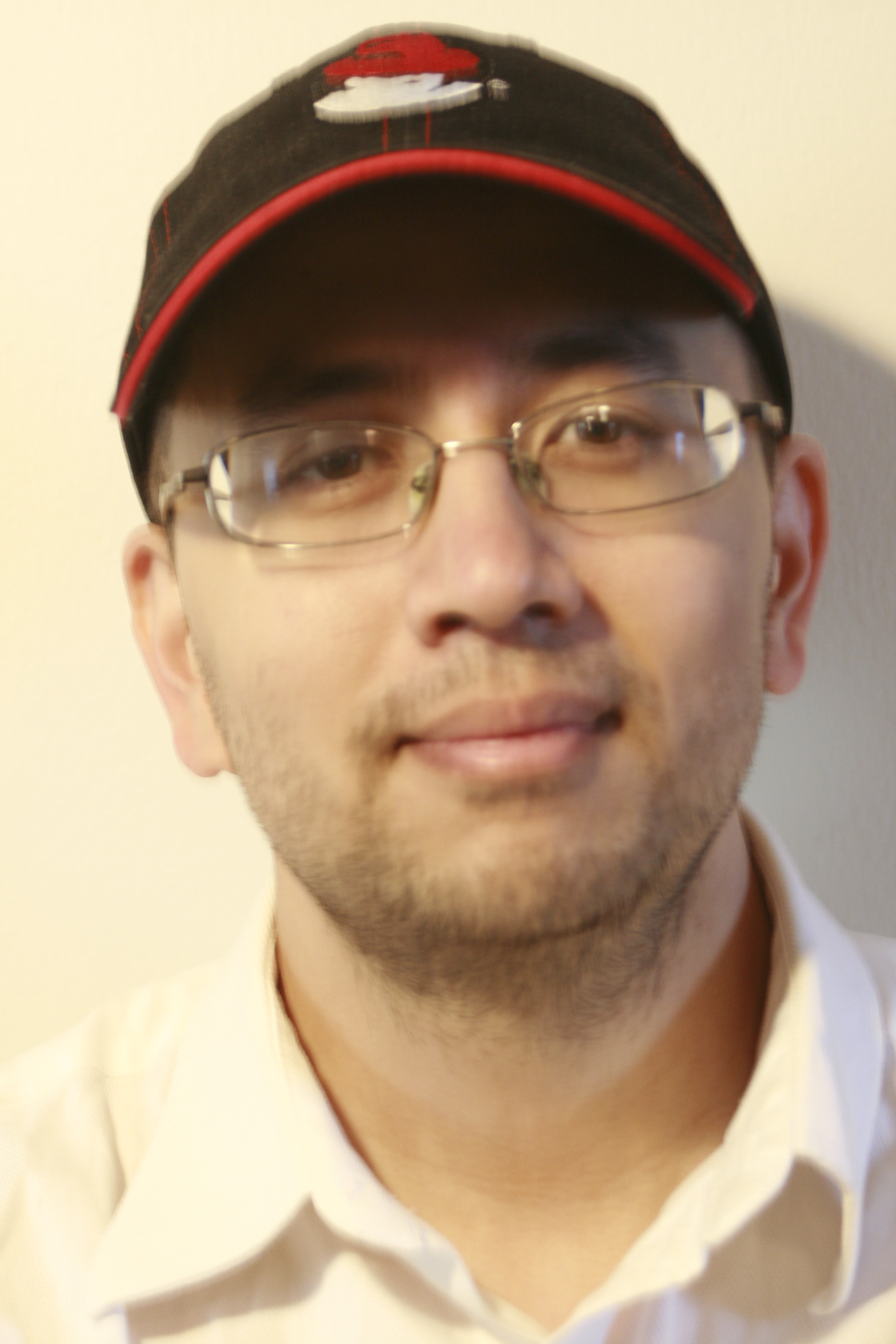 Decently lit picture of Colin's face, wearing a black-and-red Redhat hat